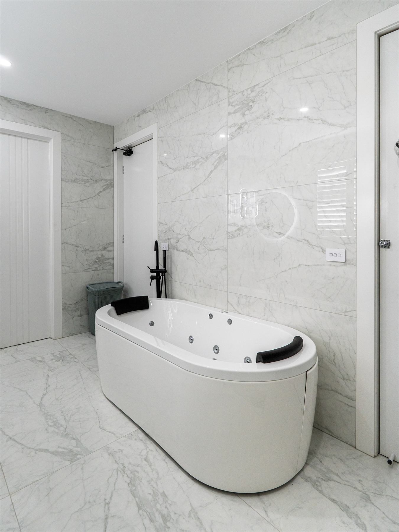 Marble-look bathroom wall and floor tiling with freestanding bath